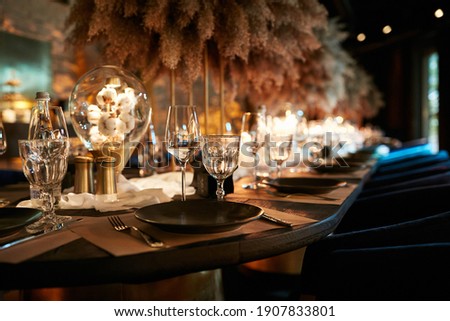 The served table in the luxury restaurant. Dark wooden table, beautiful evening restaurant with luxury rustic decor Royalty-Free Stock Photo #1907833801