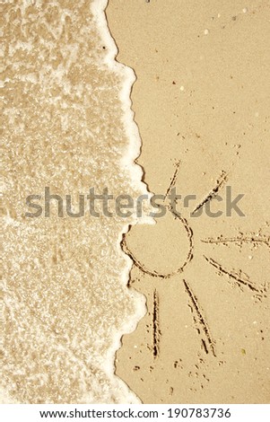 a sun drawn in the sand on the seashore 