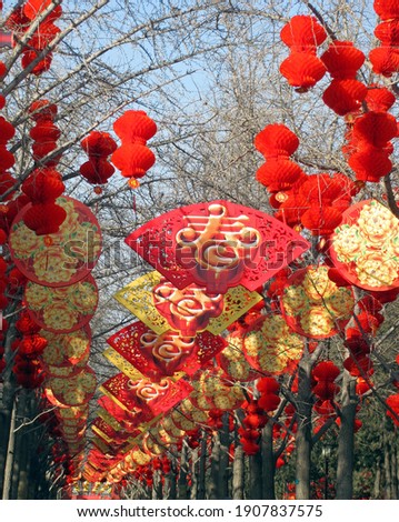Decoration for Chinese new year in Beijing, China. The big character on fan-shaped signs means "Spring", while one on tassels of lanterns means "Happiness", and the other "Treasures fill the home“.