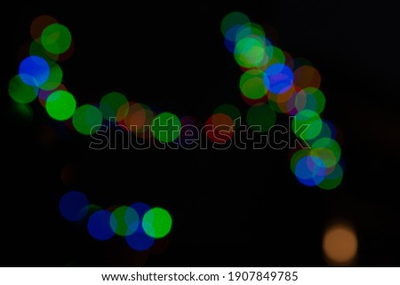 Red, green, blue and yellow bokeh effect yellow Christmas lights. Blurred abstract matrix on black background. Defocused glowing lights glitter.