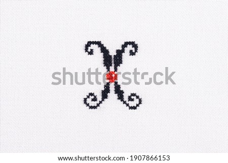 Letter X of Embroidered Cross - Stitch Latin Alphabet on White Linen Fabric Background Handmade Close-up