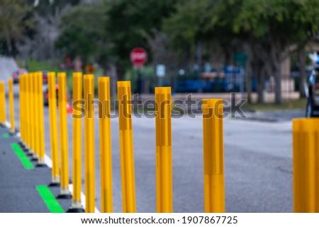 A row of bright yellow reflective metal sticks or pylons used as barricades at a road construction barrier site. The closed road signs protect the sidewalk as traffic control during roadwork.