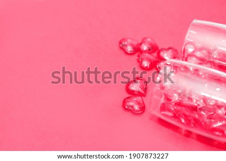 two glasses with hearts on a red background. the view from the top. red hearts spilled out of the glasses. isolated on a pink background. copy space