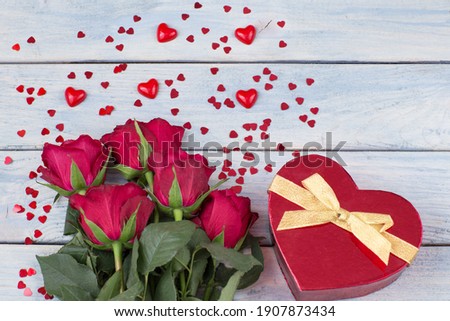 a bouquet of red roses and a gift in a box 