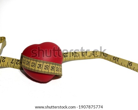 A red heart shape stress toy with measuring tape isolated on white background. 