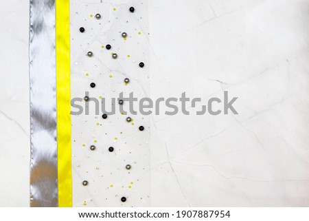 yellow and gray satin ribbon on a gray marble light background with beads in the color of the year 2021