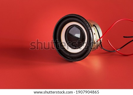 Black music sound speaker witn cable isolated on red background. Audio equipment