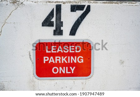 Leased Parking sign with assigned number on a white wall