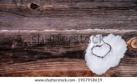 Valentine's Day background. Brown old winter wooden natural boards in with white heart made of snow. Copy space. Top view. Surface of table to shoot flat lay. Concept love, romantic relation. Banner