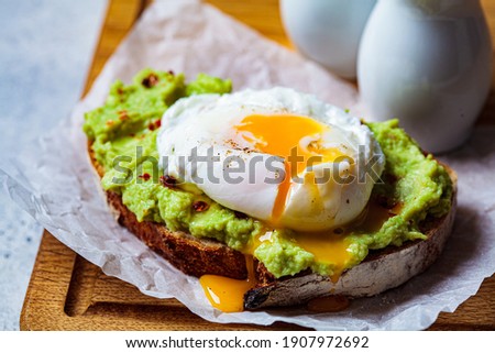 Avocado toast with poached egg on a wooden board. Breakfast concept. Royalty-Free Stock Photo #1907972692