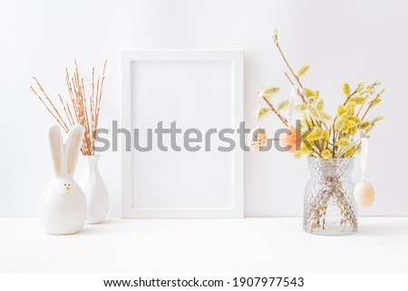 Home interior with easter decor. Mockup with a white frame and willow branches in a vase on a light background