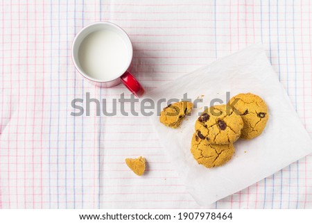 Dessert cookies made of corn flour with raisins with a cup of milk, on a light background. Gluten free food. Copy space