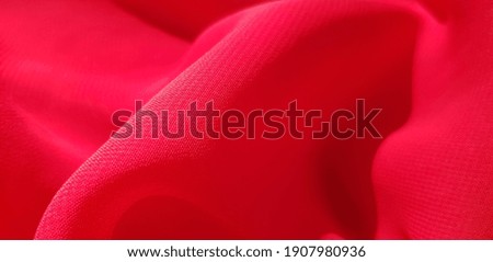 Red satin fabric in folds (texture).