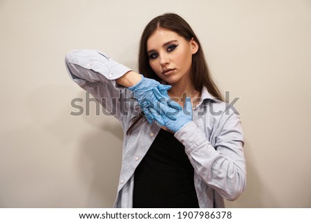 Attractive woman with blue stylish makeup with latex gloves in beauty studio