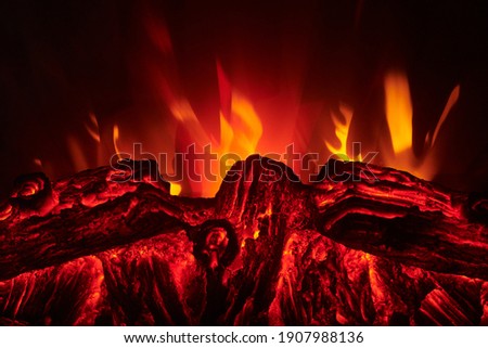 Artificial electric fireplace with orange, red and yellow flame. Fire close up view. Cozy romantic light.