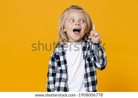Little shocked surprised wow fun happy blond long-haired kid boy 4-5 years old wearing casual clothes isolated on bright yellow wall color background children studio portrait. People childhood concept
