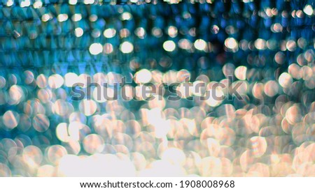 Golden spectrum bokeh lights on blue blurred background with copy space. Shiny defocused circle lights as Christmas backdrop