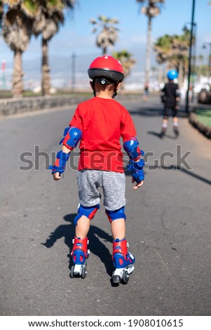 Back view of little boy practicing with roller-skates