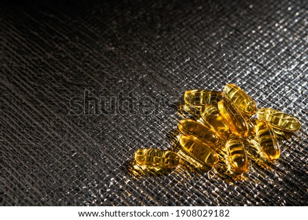 Omega-3 capsules lie on a shiny textured background. Fish oil tablets. Health support, vitamins and treatments. Health care concept, copy space