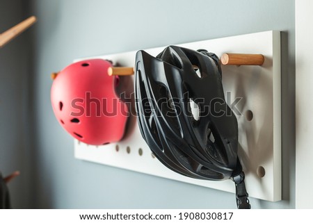 Bicycle helmets for adults and kids hang on a stylish hanger. Safety of children and adults while cycling