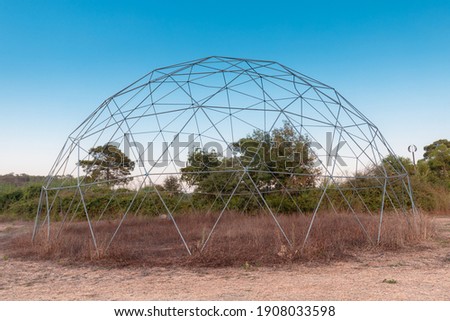 The steel frame of a geodesic dome is built on nature. Such a frame has a large load-bearing capacity and wind resistance Royalty-Free Stock Photo #1908033598