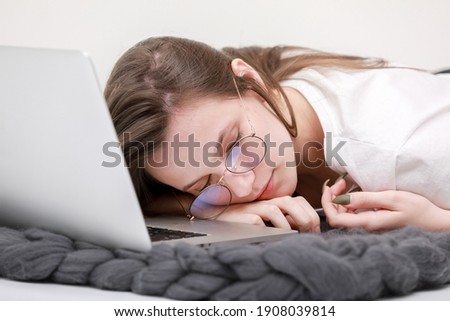 Sleeps in the workplace. Tired young woman working, headache, falling asleep on white background. Learns, using laptop computer on table. Freelance. Writing, typing. Technology concept. Paperwork.