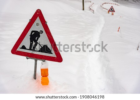 A closeup shot of a road works sign for construction in the snow