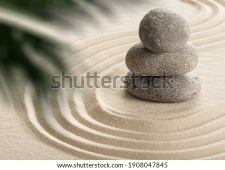 Pyramids of gray zen stones on the white sand with abstract wave drawings. Concept of harmony, balance and meditation, spa, massage, relax. Royalty-Free Stock Photo #1908047845