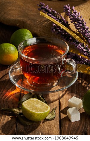 Tea in a white cup next to lime and flowers on a wooden background Royalty-Free Stock Photo #1908049945