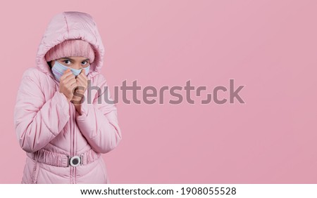 Coronavirus, Covid-19. funny girl In Protective Face Mask Coughing In Elbow Standing On pink  Studio Background, Wearing Winter Clothes. Corona Virus And Flu Epidemic Season. Copy Space