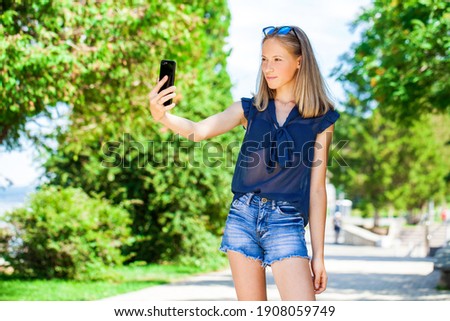 Young beautiful girl taking pictures of herself on a mobile phone