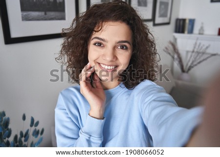 Happy pretty hispanic gen z teen girl holding smartphone looking at camera taking selfie shot for social media, making video call at home by virtual mobile app. Close up face headshot portrait. Royalty-Free Stock Photo #1908066052