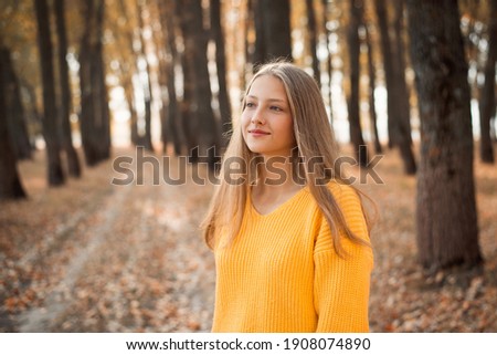 Portrait of a girl in bright autumn park. Atmospheric warm autumn picture of a beautiful teenage girl in yellow sweater