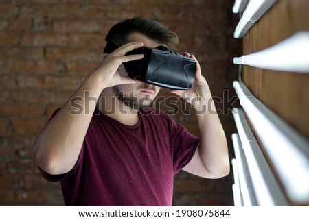 Young guy in virtual reality glasses near glowing fluorescent lamps