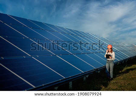 Inspector Engineer Woman Holding Digital Tablet Working in Solar Panels Power Farm, Photovoltaic Cell Park, Green Energy Concept. Royalty-Free Stock Photo #1908079924