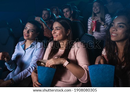 Group of cheerful people laughing while watching movie in cinema. Royalty-Free Stock Photo #1908080305
