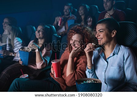 Group of cheerful people laughing while watching movie in cinema. Royalty-Free Stock Photo #1908080320