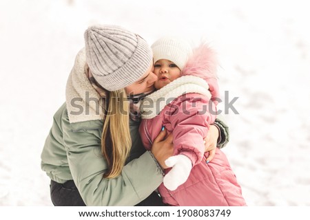 Young mother holds her little daughter in her arms and kisses her. Family portrait. Motherhood and childhood