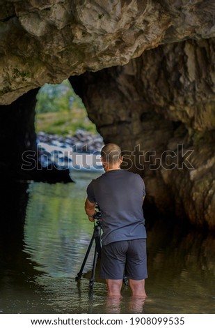 Professional photographer taking picture inside of a cave with lake inside