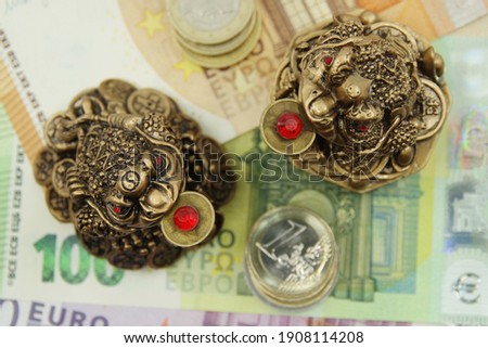 Two Chinese Feng shui frogs sitting on euro banknotes. Symbol of abundance and luck. 