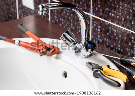 plumbing faucet repair concept. plumber using wrench tool and pliers to adjusting tap leak at bathroom. diy plumber conceptual. Royalty-Free Stock Photo #1908136162