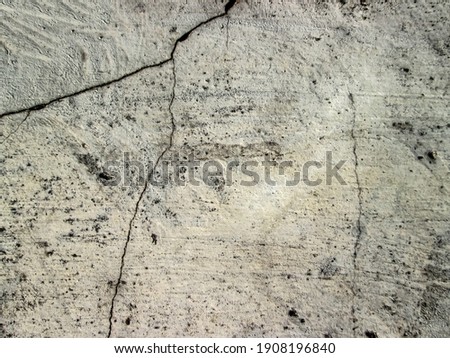 A crack in a white concrete wall. Destroyed old building. The effect of an abandoned construction site. Rough granular concrete. Stock photo of damages.