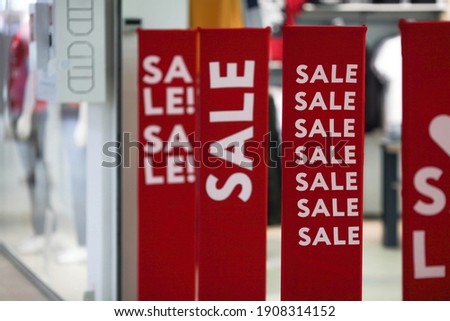 Red bright sale banner on anti-thieft gate sensor at retail shopping mall entrance. Seasonal discount offer in store. Discounts and black friday concept.
