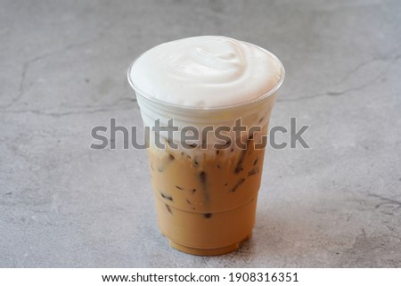 Iced cappuccino in a plastic mug Laid on the old cement floor Royalty-Free Stock Photo #1908316351