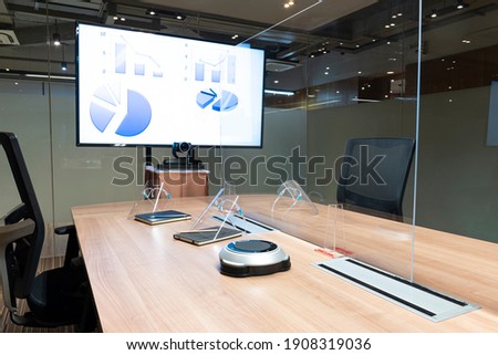 Video conference meeting room with clear acrylic sheet separates the center on the conference table to prevent COVID-19 and face shield on the table. 