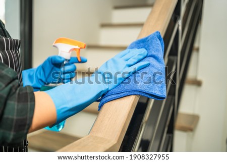Housekeeper cleaning railing by using alcohol and liquid cleaning solution, disinfection and hygiene concept. Royalty-Free Stock Photo #1908327955