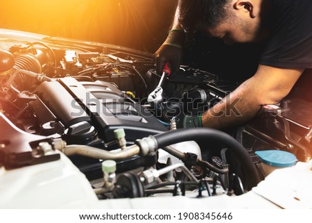 The Mechanic hand wearing black gloves is fasten the bolt with the socket wrench to repairing of the car engine Royalty-Free Stock Photo #1908345646