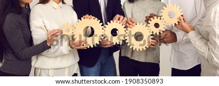 Teamwork, partnership, international cooperation concept. Hands of different ethnicity people business team or students friends holding various wooden gears as symbol of unity, support, common goals