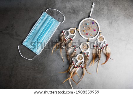 Dreamcatcher and Face mask on Gray-black cement floor background with copy space.Concept to protect good luck from COVID-19