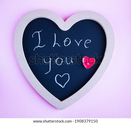 chalk board in the shape of a heart for copying space or writing congratulation text, with various red and pink accessories in the shape of a heart, for a postcard or congratulations on Valentines Day